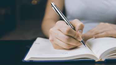 photo of person writing on notebook